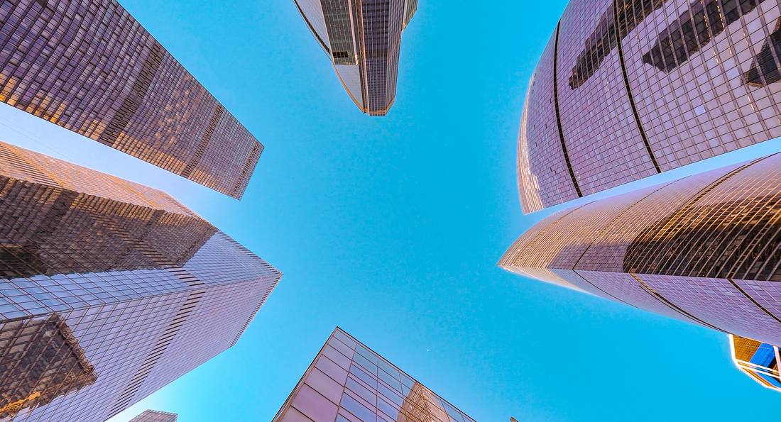 Glass office towers seen from street level, converging on an open sky